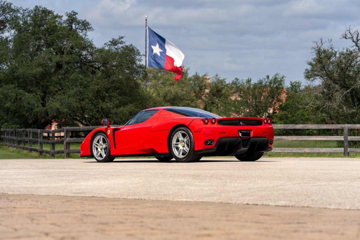 Red 2003 Ferrari Enzo with silver rims under the Texas flag.
