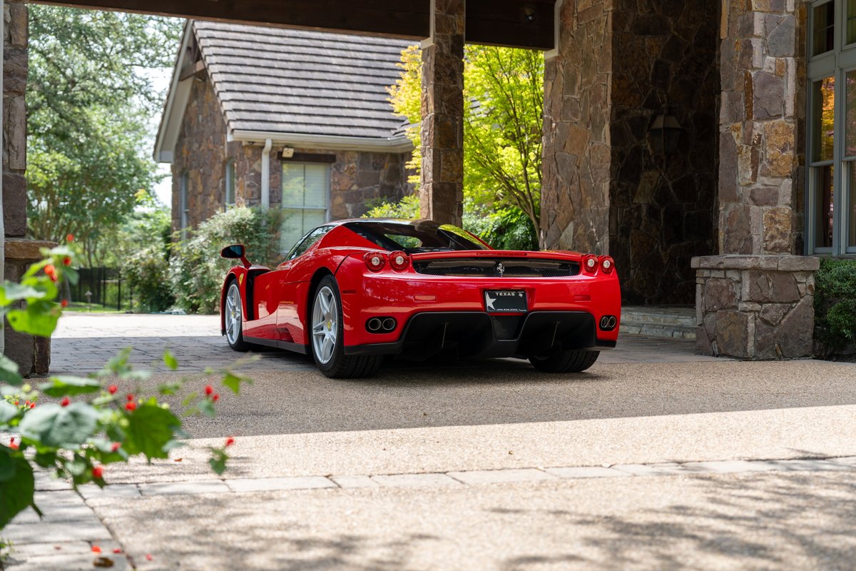 Rosso Corsa Ferrari Enzo with silver rims, parked under a stone portico.