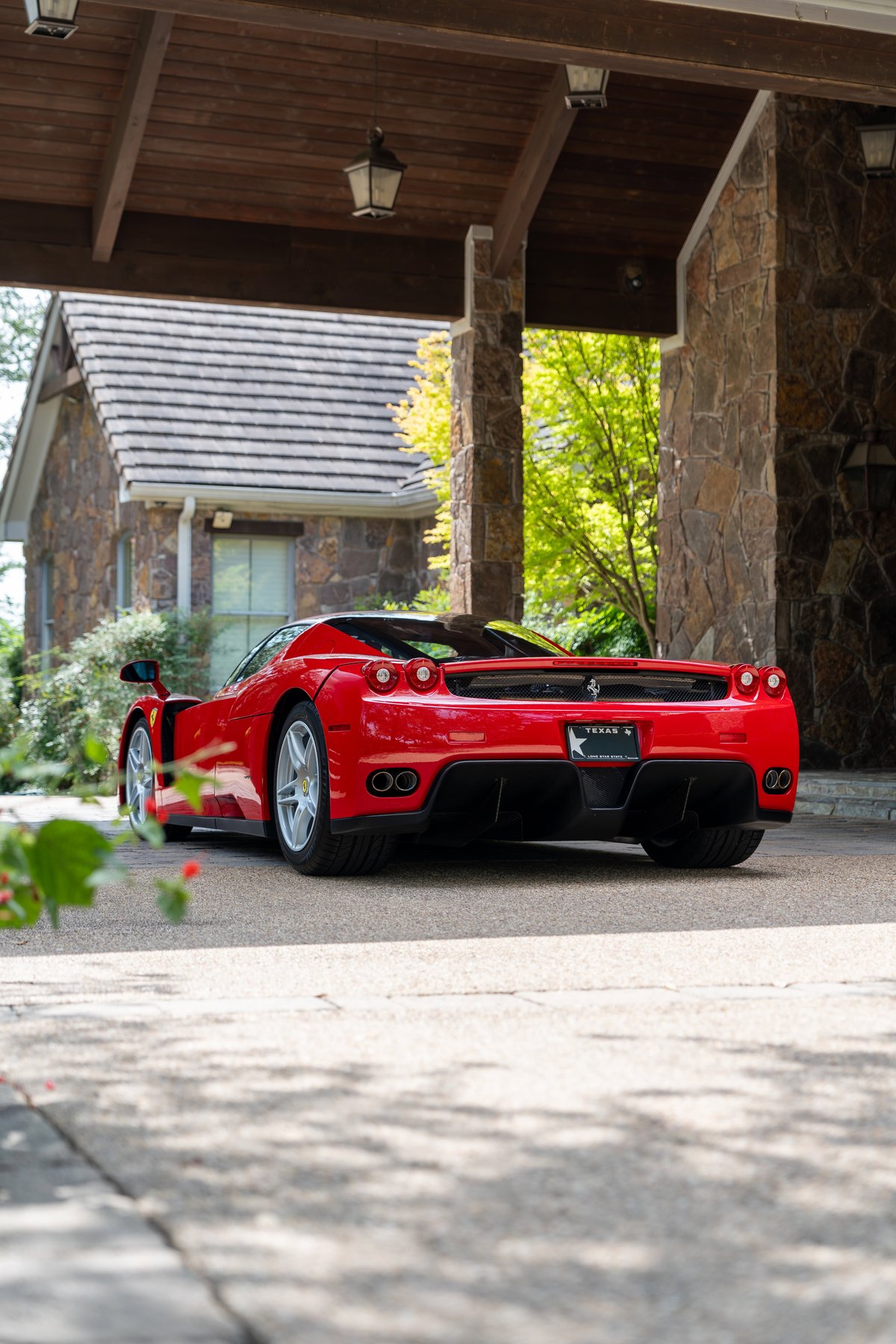 Rear view of a red Ferrari Enzo with silver rims and quad exhaust pipes.