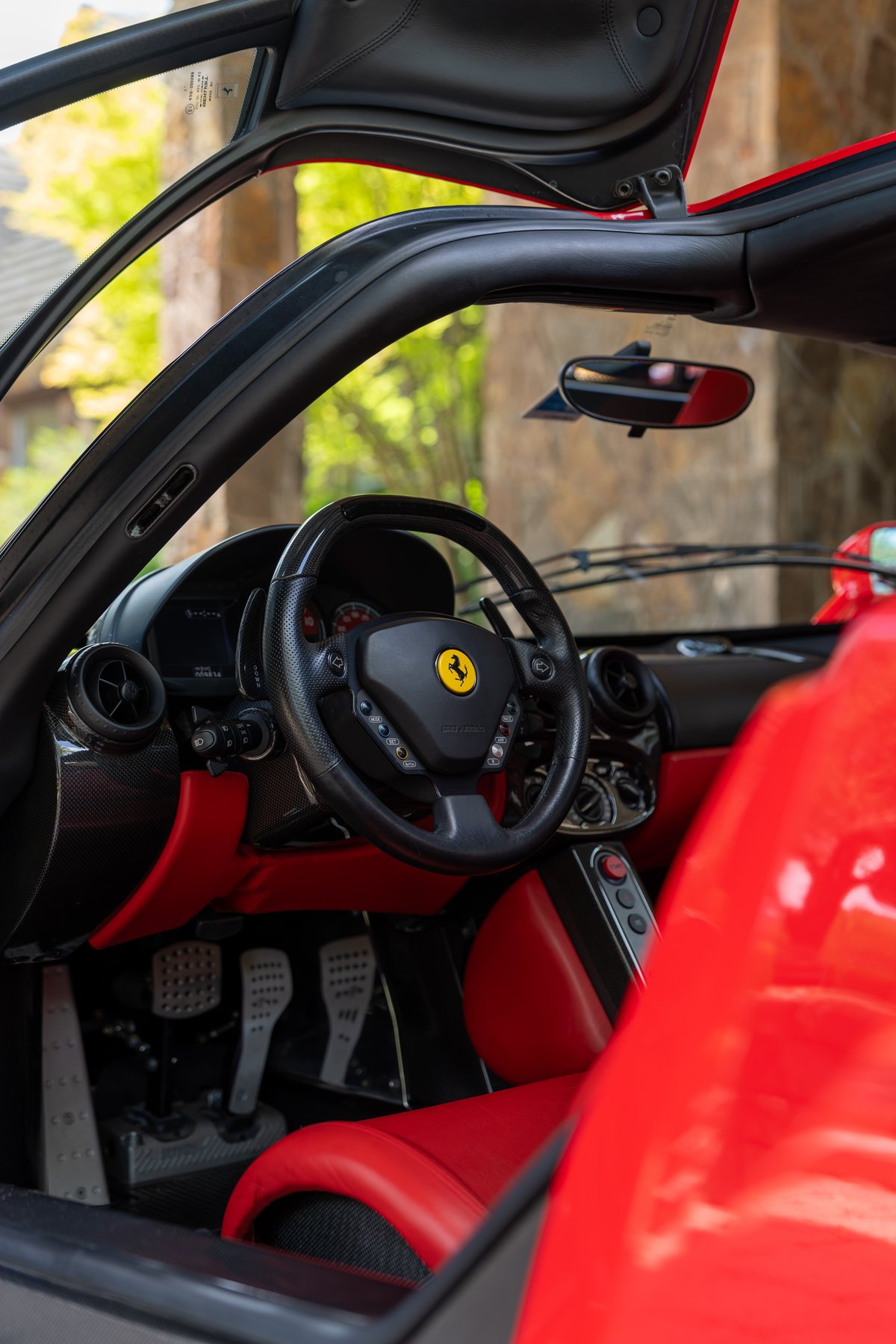Rosso Corsa 2003 Ferrari Enzo interior with red leather trim, carbon fiber accents, and aluminum pedals.
