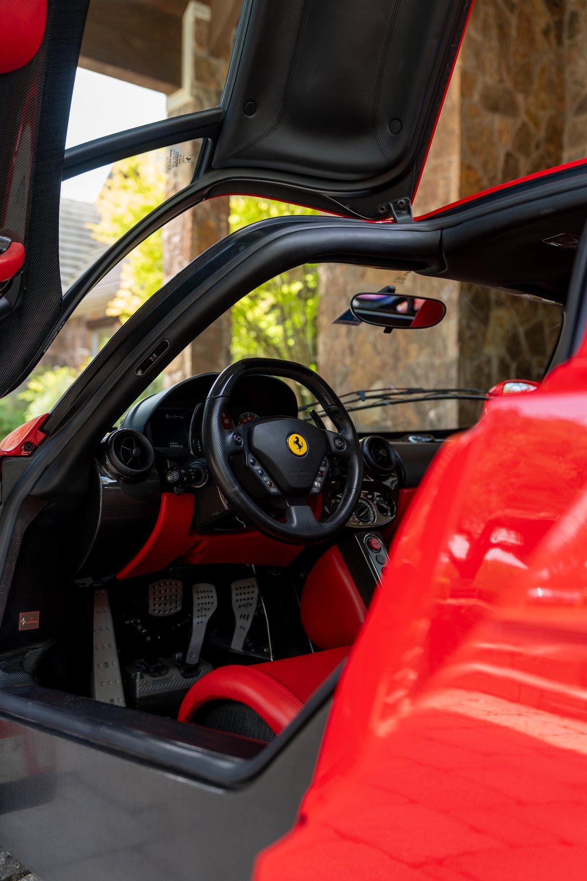 Rosso Corsa 2003 Ferrari Enzo interior with red leather seats, carbon fiber trim, and aluminum pedals.