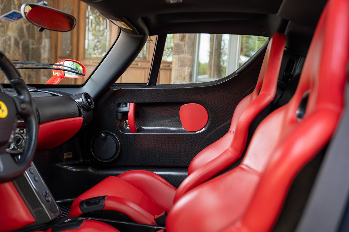 Interior of a red 2003 Ferrari Enzo featuring red leather racing seats and carbon fiber trim.