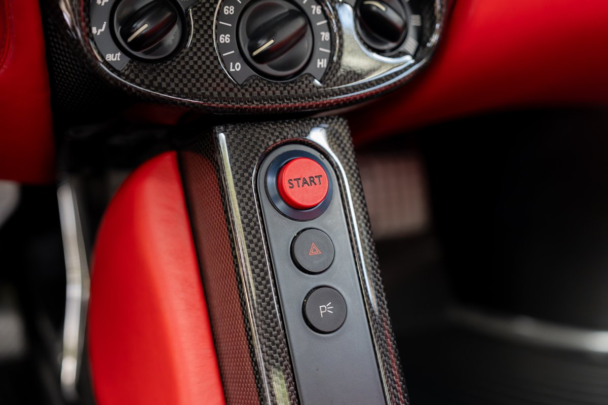 Red Ferrari Enzo interior with carbon fiber trim, red leather seats, and a red start button.