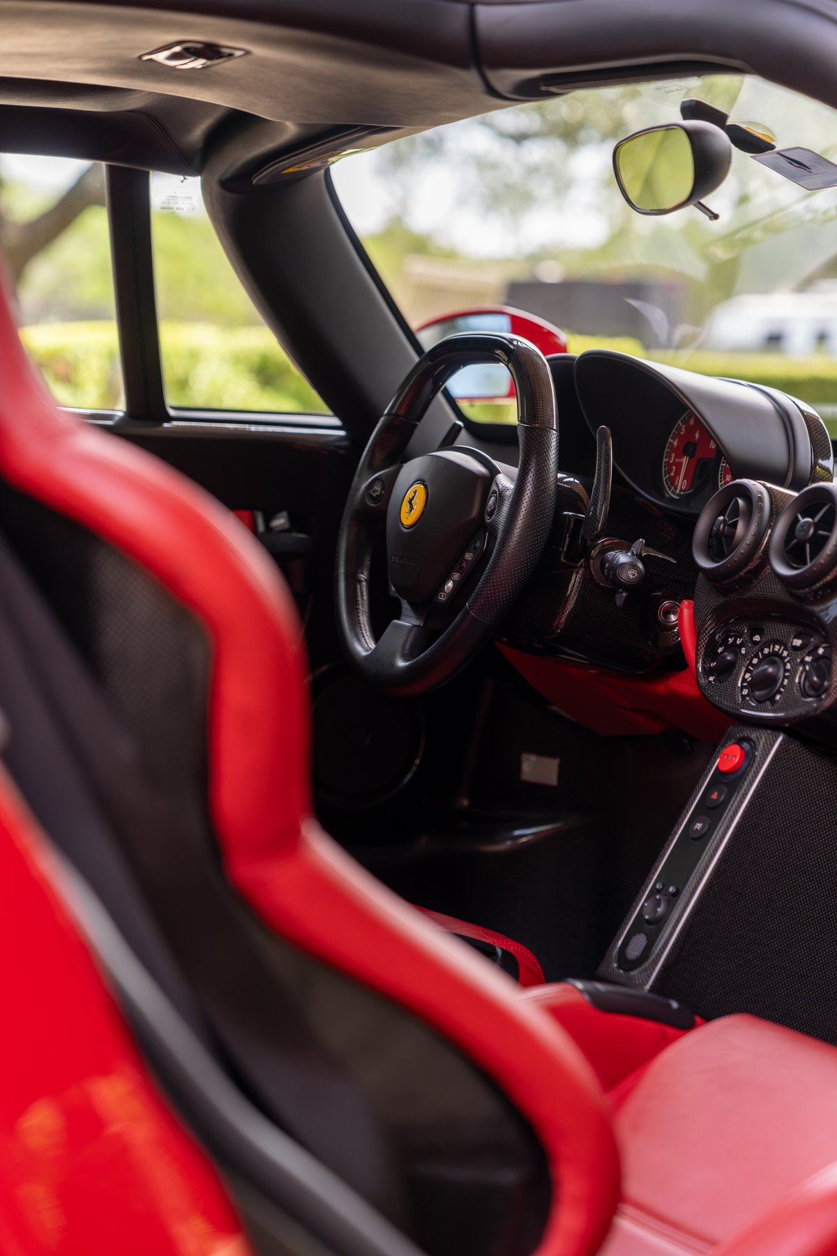 Rosso Corsa Ferrari Enzo interior: racing seats, carbon fiber trim, and F1 steering wheel.