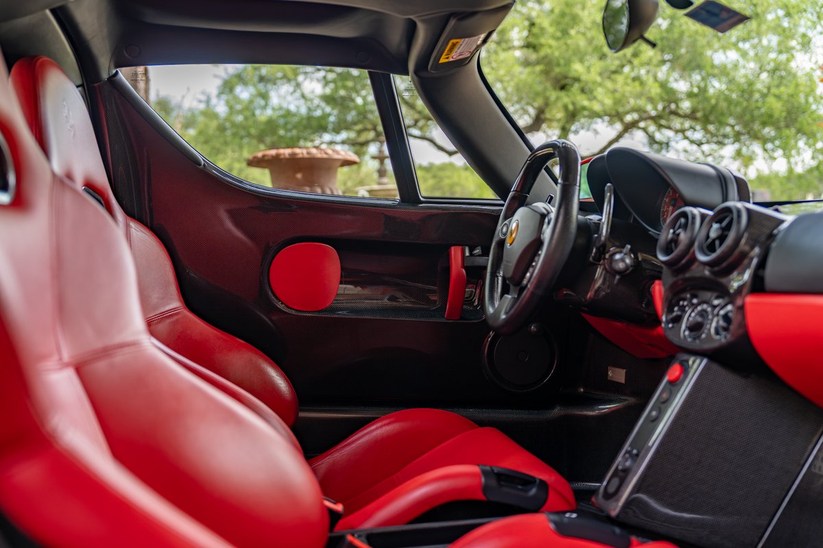 Interior view of a Rosso Corsa 2003 Ferrari Enzo with red leather seats and carbon fiber trim.