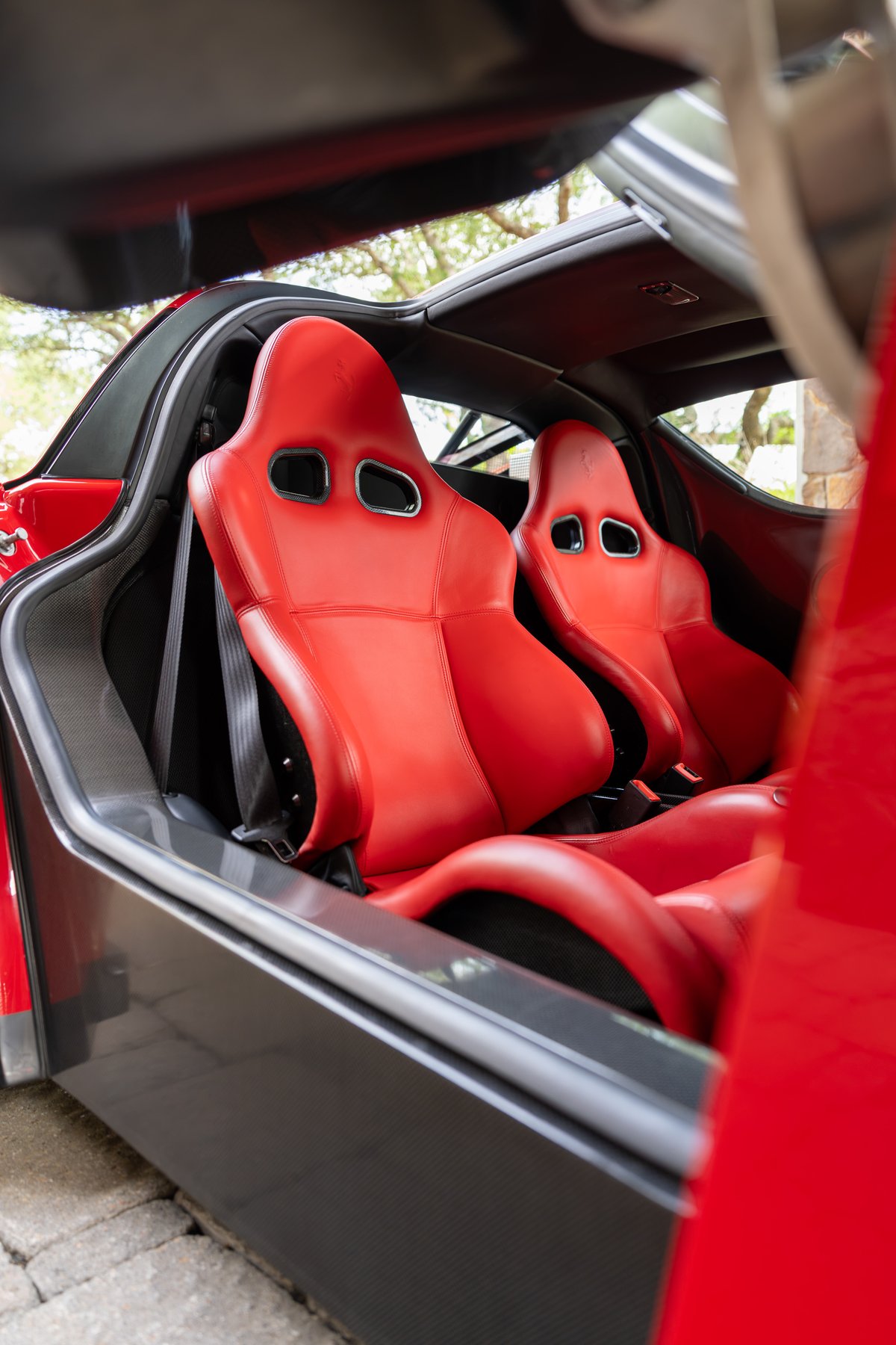 Rosso Corsa 2003 Ferrari Enzo interior with red leather bucket seats and carbon fiber trim.