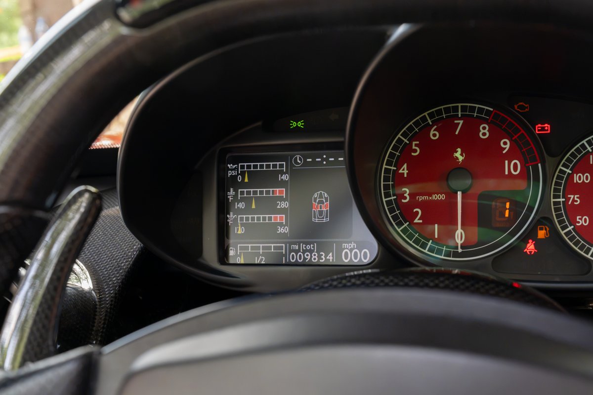 Ferrari Enzo dashboard: Red tachometer, digital display, carbon fiber trim, paddle shifters.