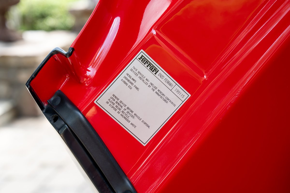 Close-up of a Rosso Corsa Ferrari Enzo's VIN plate and hood latch.
