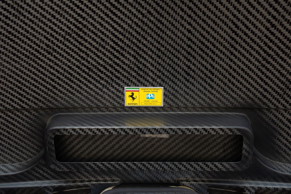 Close-up of a yellow sticker on the carbon fiber weave of a 2003 Ferrari Enzo.