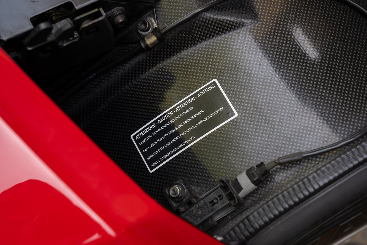 Close up of a red Ferrari Enzo carbon fiber interior with an airbag warning sticker.