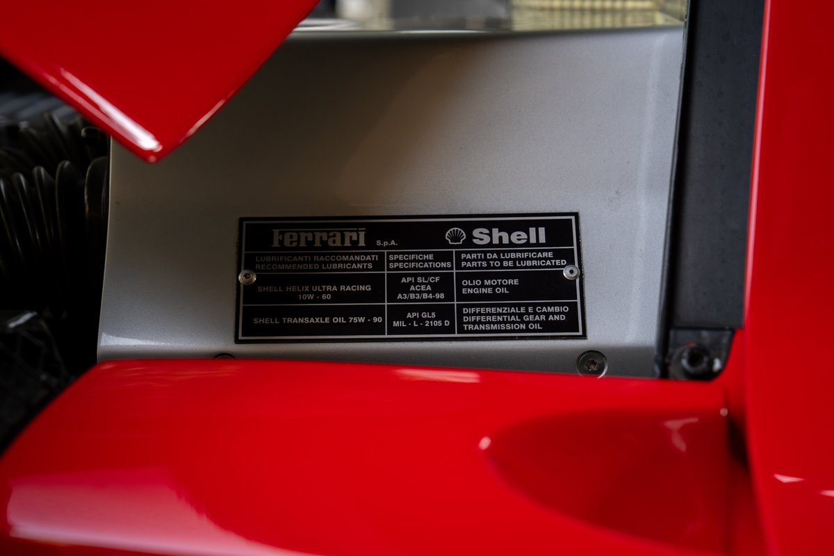 Close-up of the Ferrari Enzo's metal engine bay cover with Shell oil specification sticker.
