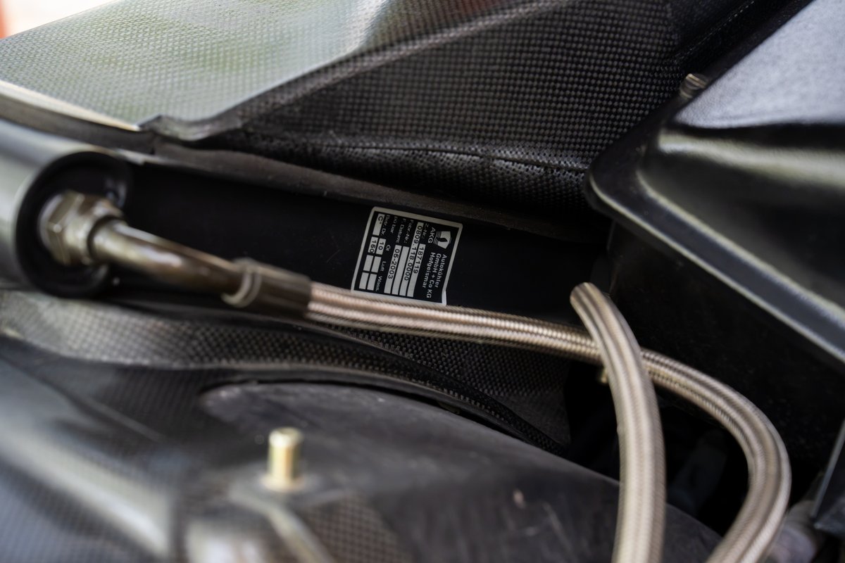Ferrari Enzo's carbon fiber dash with metal brake lines and identification tag.