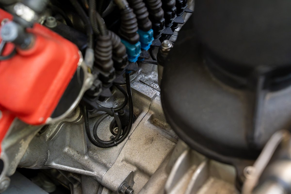 Close-up of the engine bay of a red 2003 Ferrari Enzo, showing ignition coils and intake manifold.