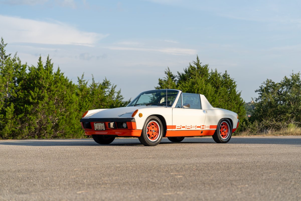 A white 1974 Porsche 914 Can-Am with orange trim and rims.