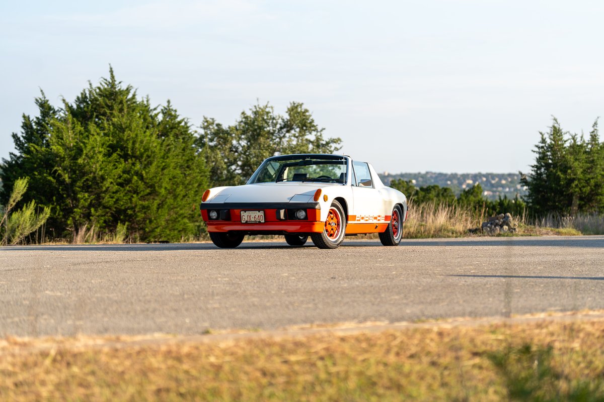 1974 Porsche 914 Can-Am Le with orange trim and rims, parked on a road.