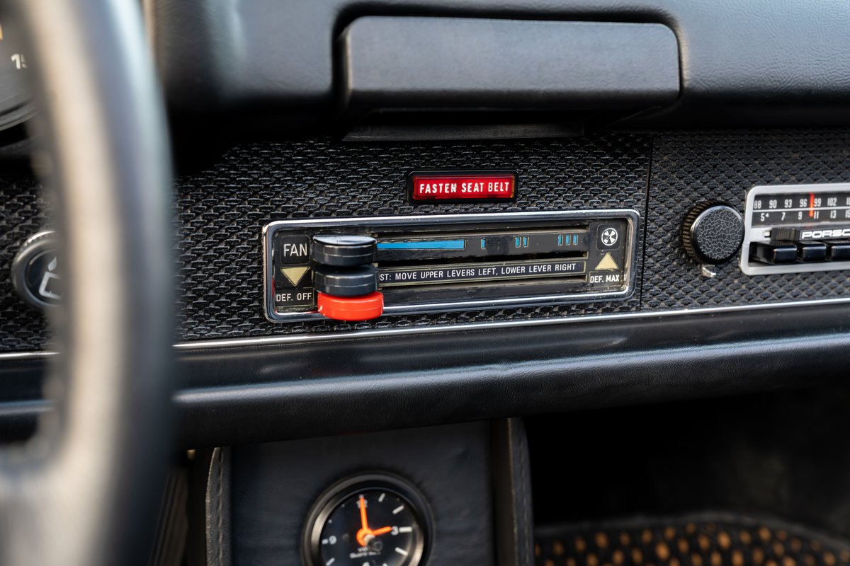 1974 Porsche 914 center console: vintage fan control, radio, and "Fasten Seat Belt" warning light.