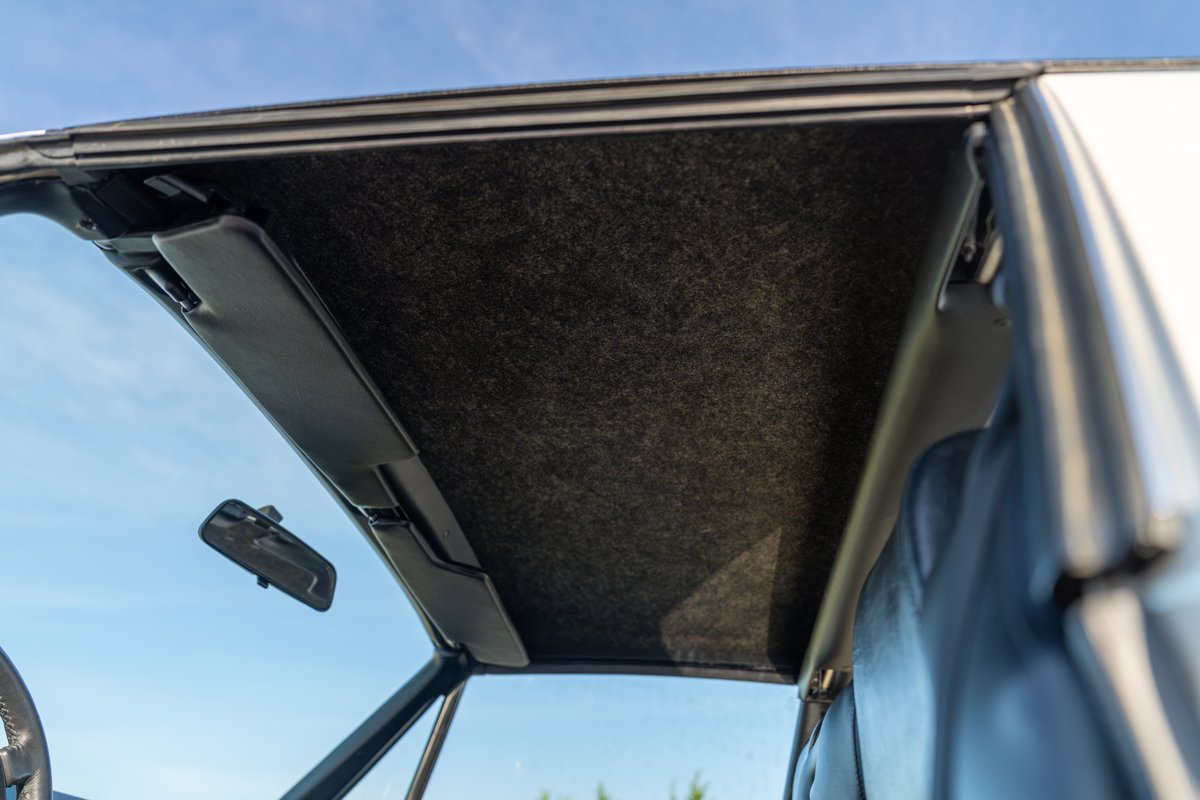 Interior shot of a 1974 Porsche 914 convertible with a dark headliner and sun visors.