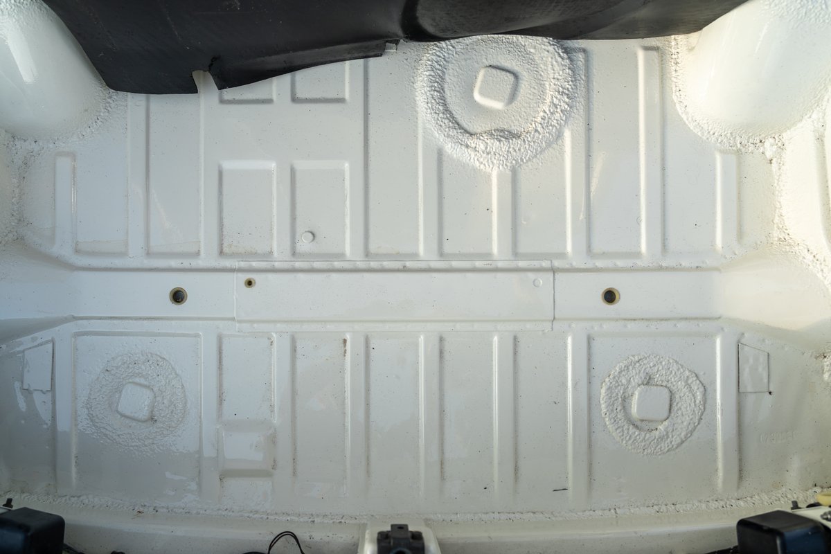 White painted underside of a 1974 Porsche 914 Can-Am LE, showing reinforced body panels and rear seat mounts.