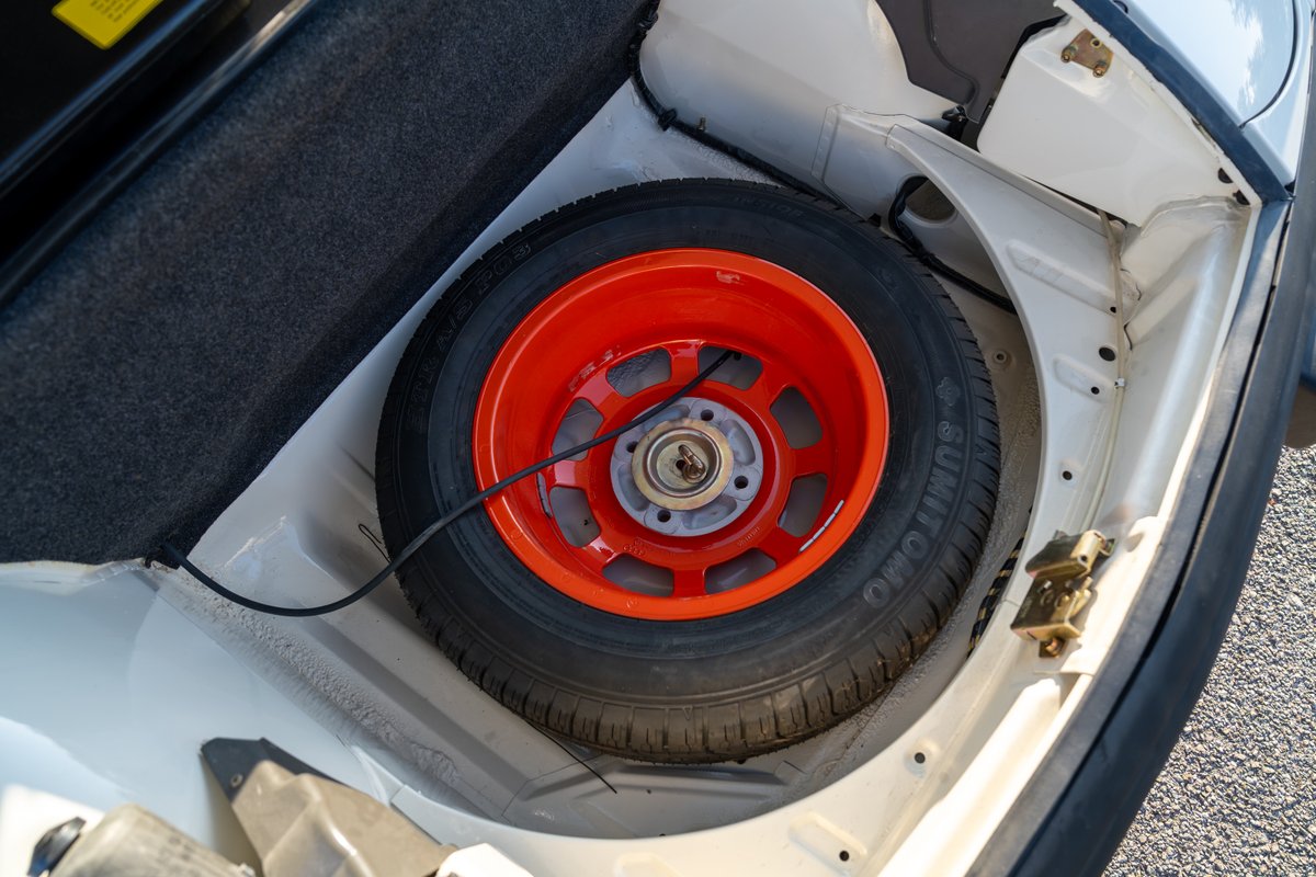1974 Porsche 914 Can-Am spare tire with orange painted rim in the trunk.