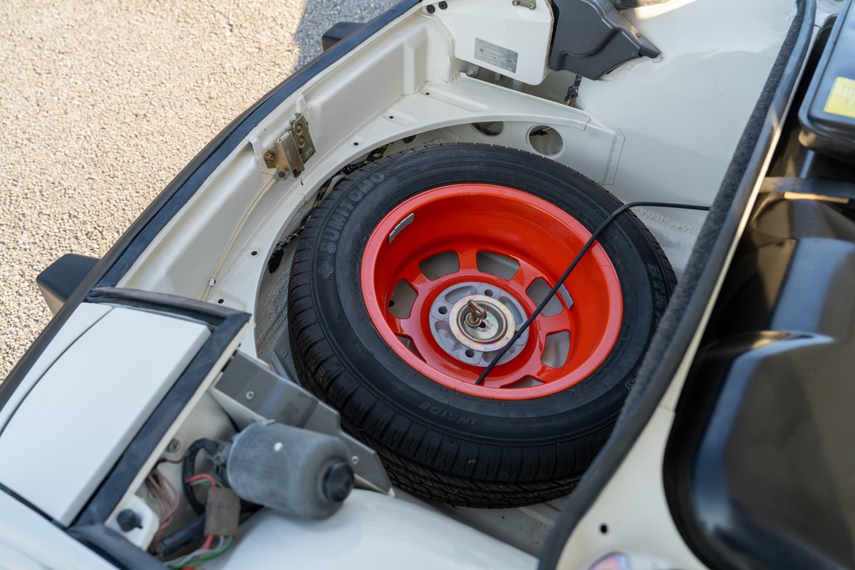 Spare tire with orange rim in the front trunk of a cream 1974 Porsche 914 Can-Am LE.