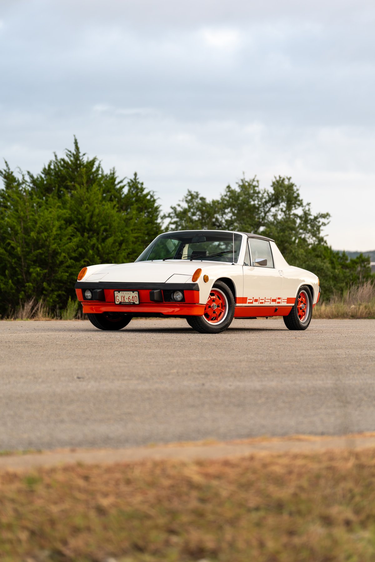 White 1974 Porsche 914 Can-Am with orange racing livery, front bumper, and rims.