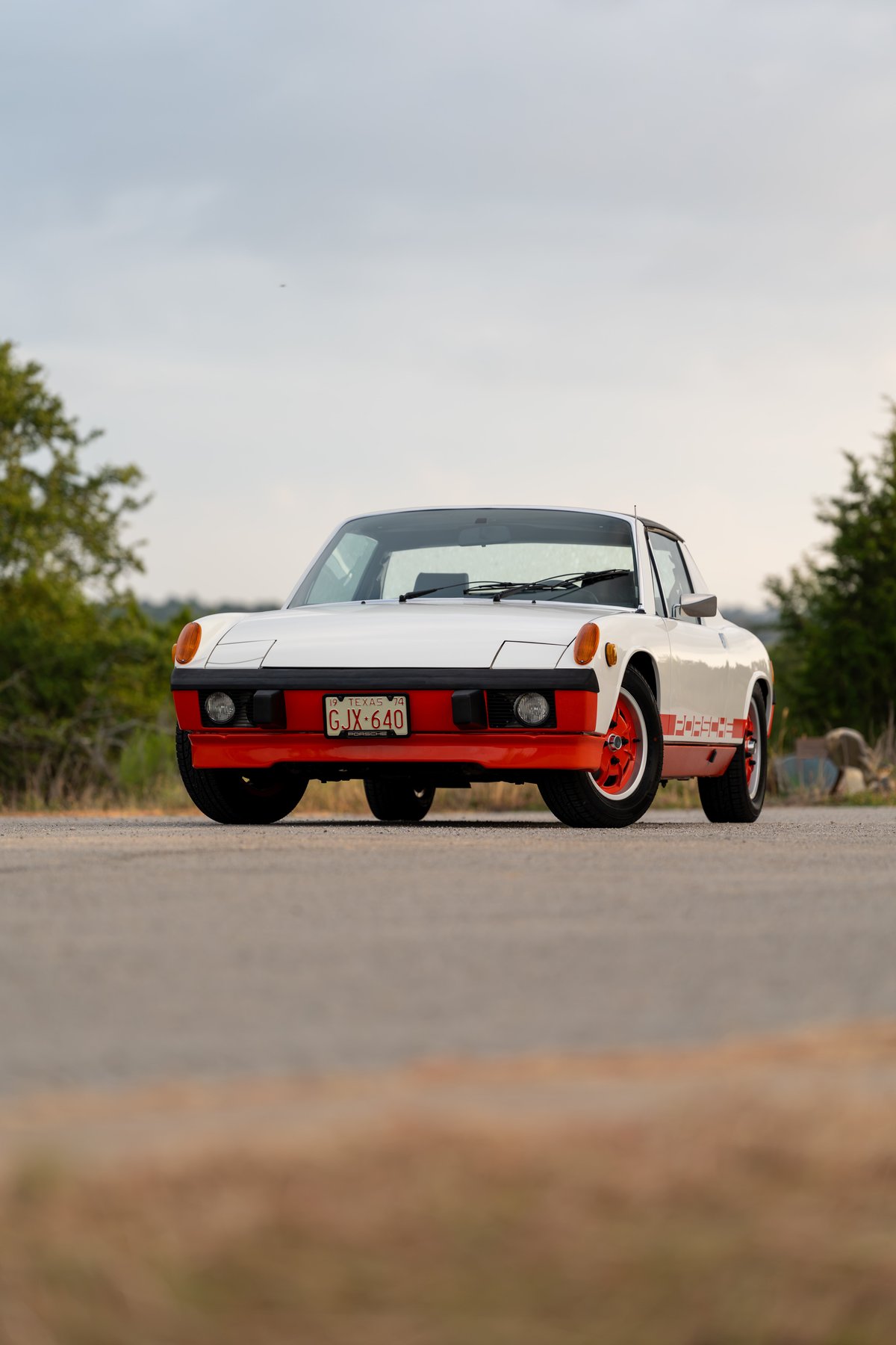 White 1974 Porsche 914 with orange racing livery, trim, and rims.