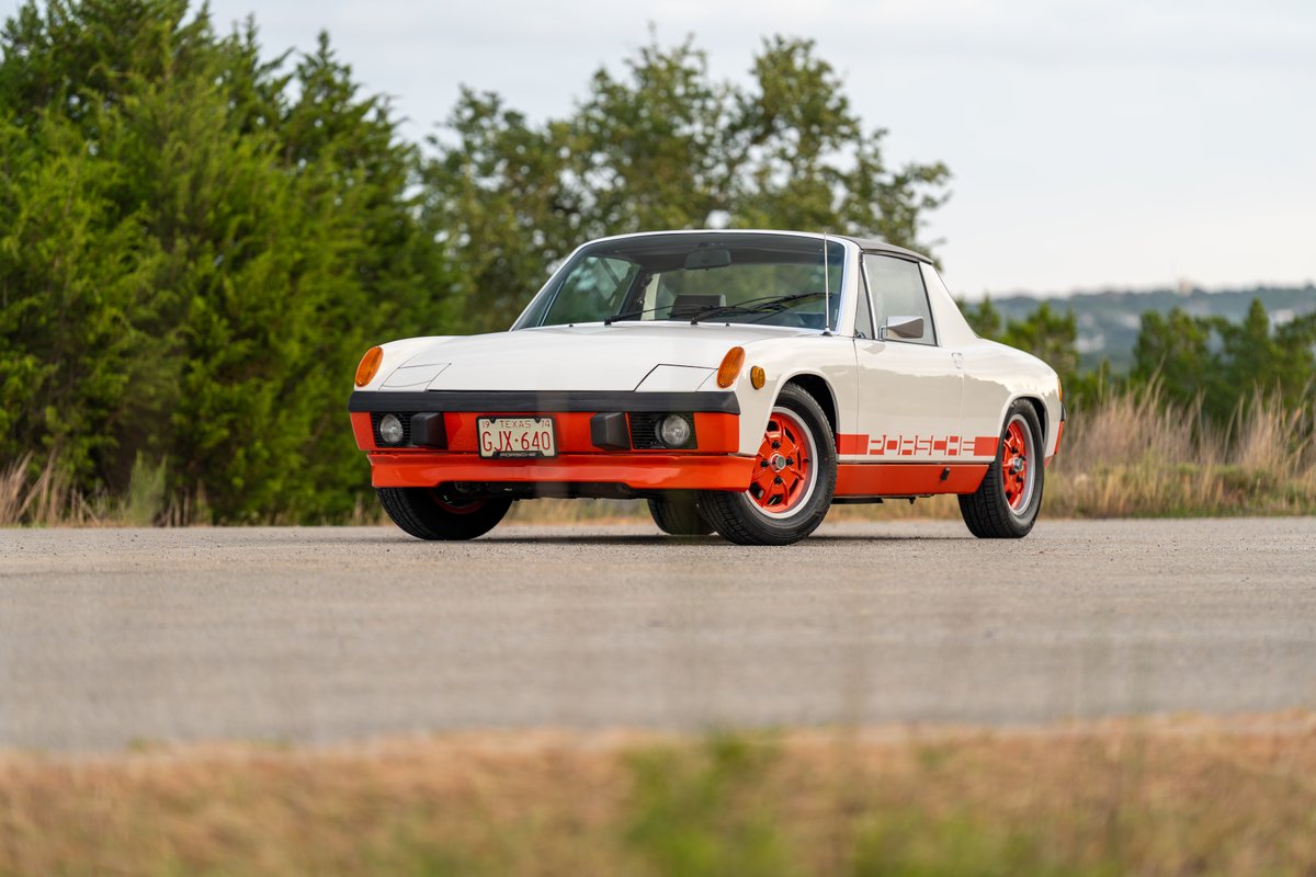 White 1974 Porsche 914 Can-Am with orange trim and "PORSCHE" livery on wheels.