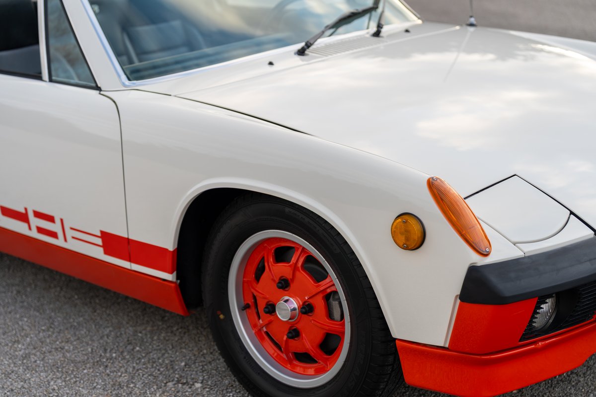 White 1974 Porsche 914 Can-Am with orange accent trim and livery on red rims.