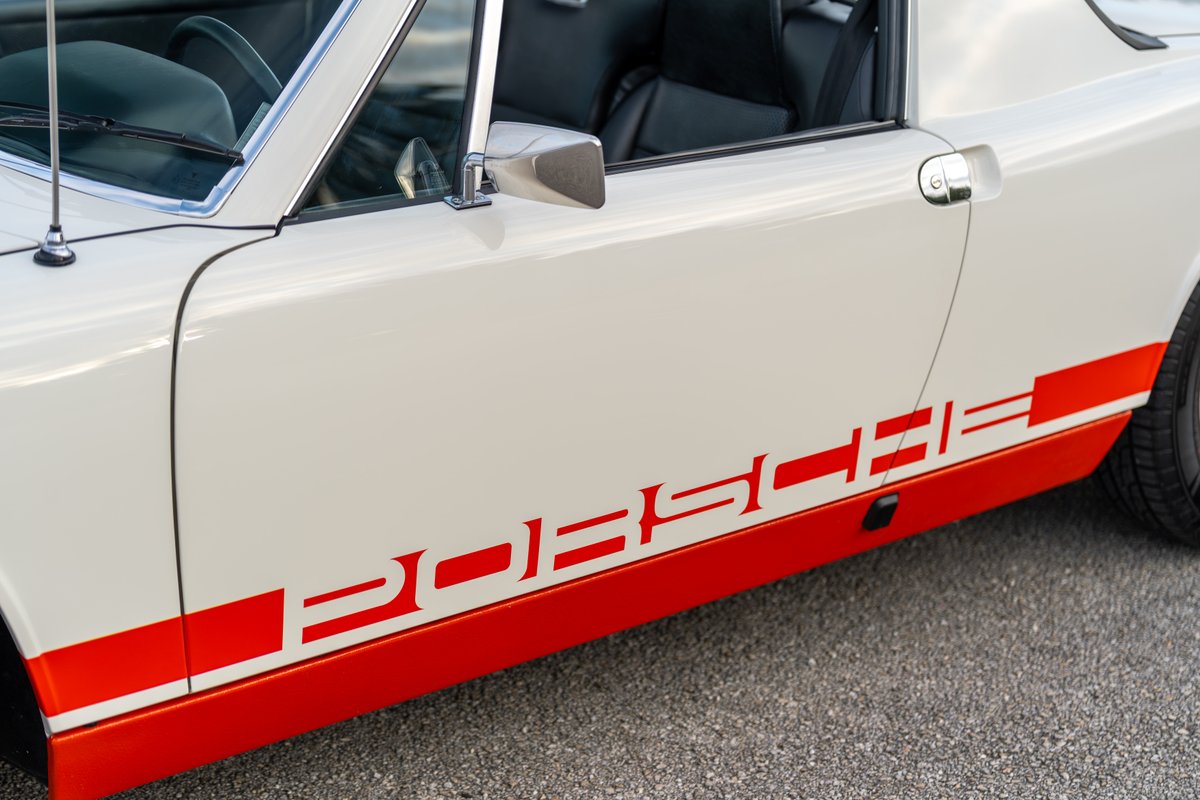 White 1974 Porsche 914 with red stripe livery and Porsche lettering.