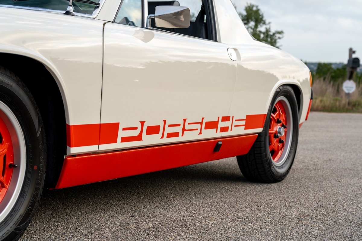 Close-up of a white 1974 Porsche 914 Can-Am with orange livery and rims.