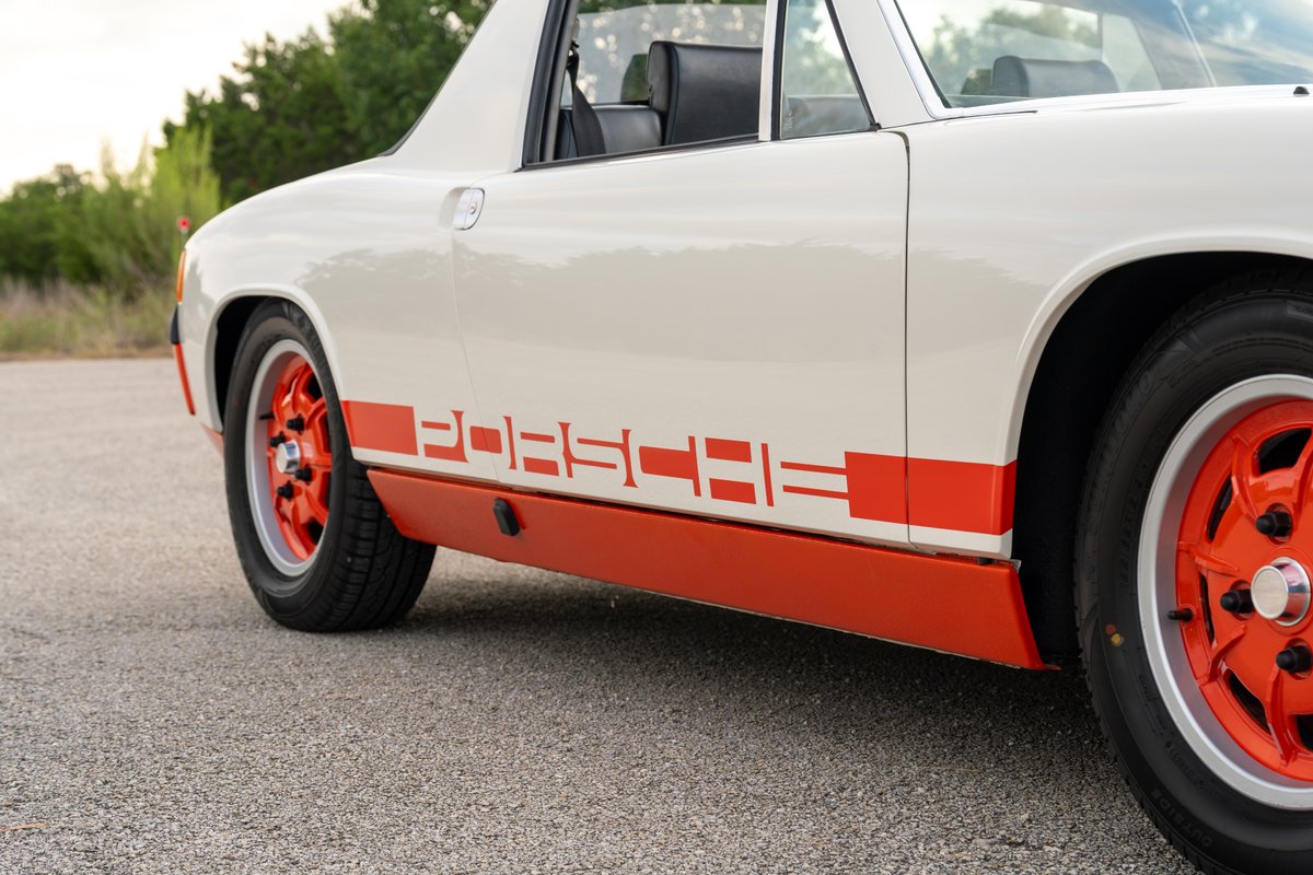 White 1974 Porsche 914 with orange racing livery and orange rims.