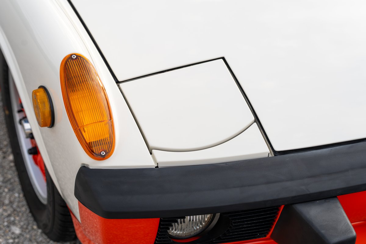 Front corner of a white 1974 Porsche 914 Can-Am with orange accents and black bumper trim.