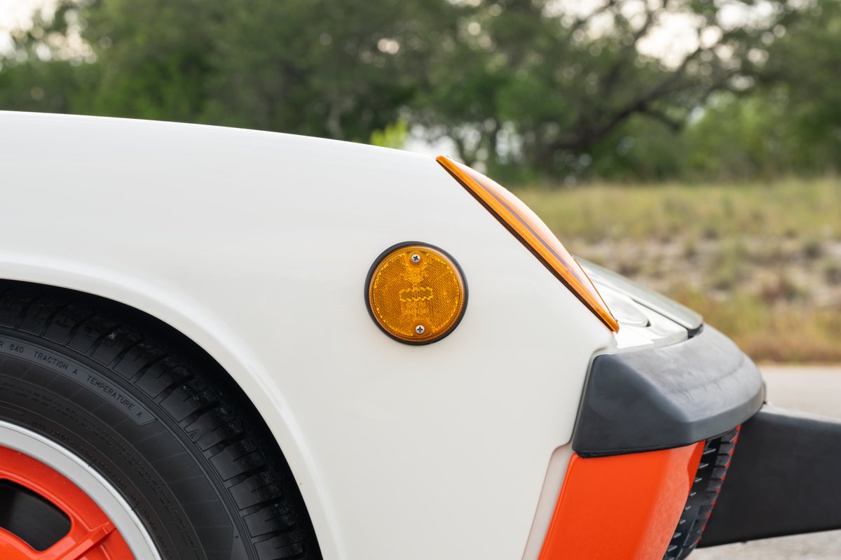 Close-up of a white 1974 Porsche 914 Can-Am with orange accents and front marker light.