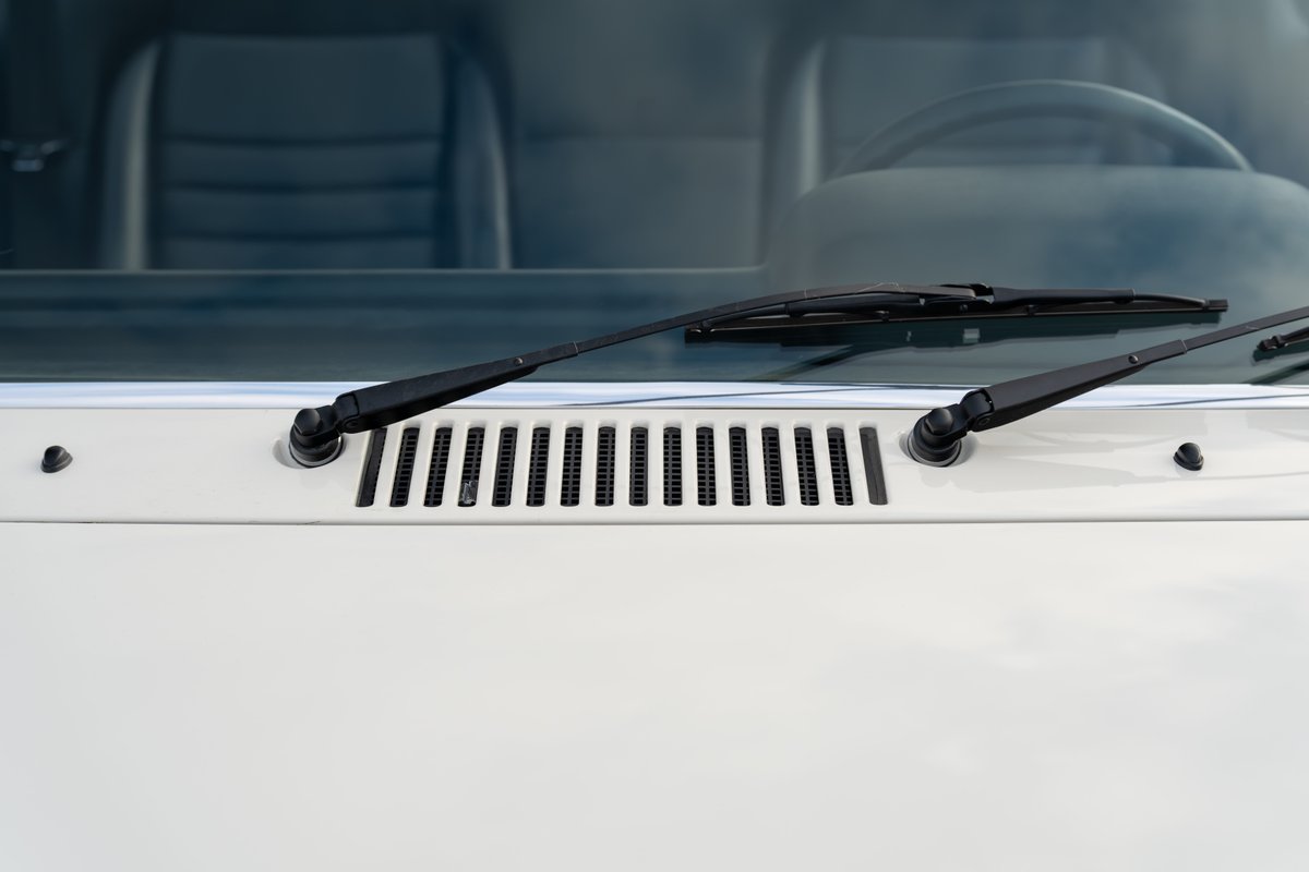 Close-up of a white 1974 Porsche 914 windshield wipers and vent grille.