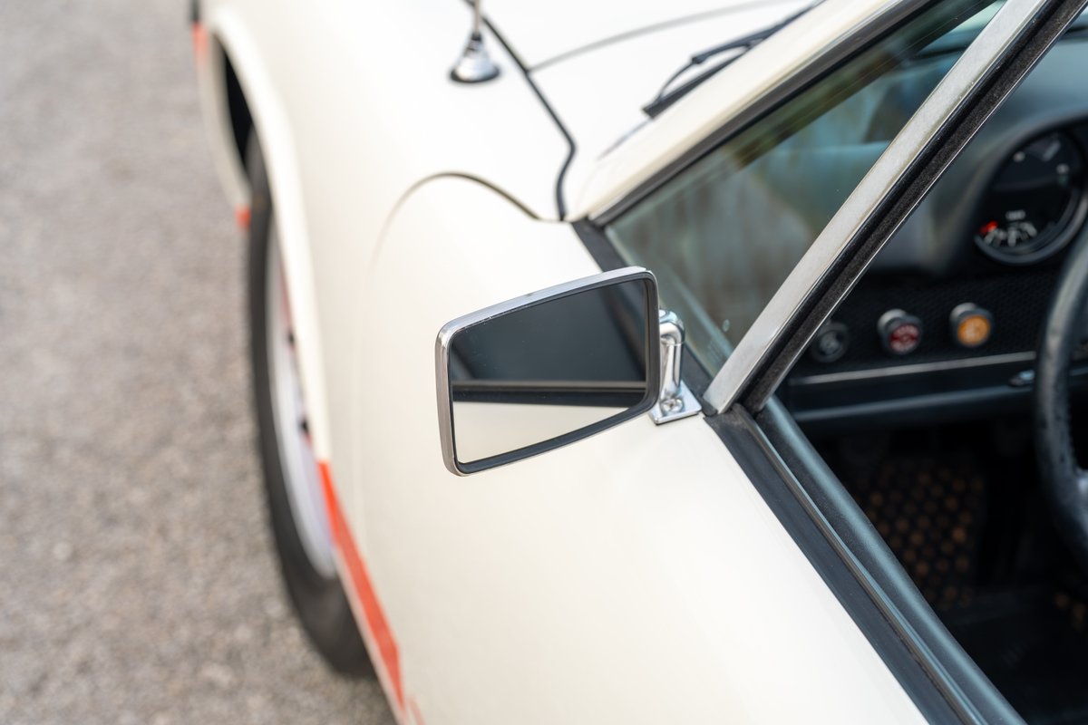 White 1974 Porsche 914 with orange stripe livery, chrome side mirror.