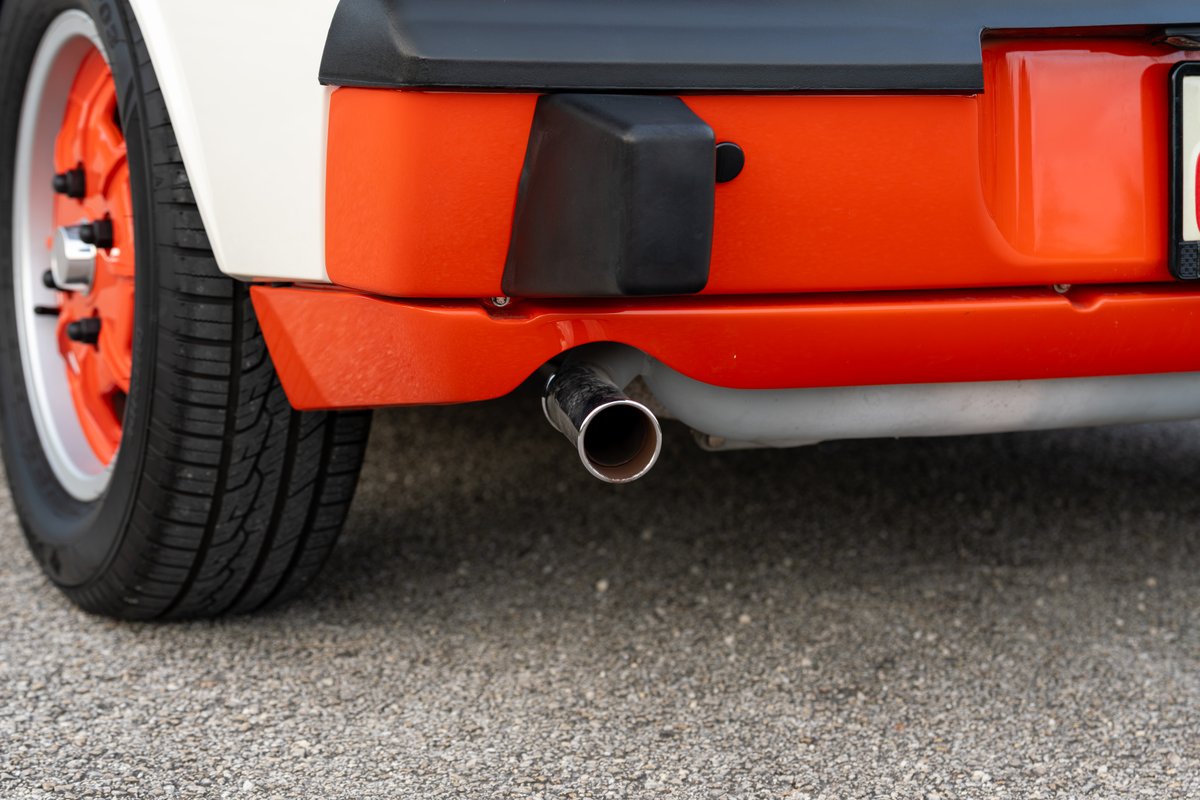 1974 Porsche 914 with orange accent trim, showing rear wheel with orange rims and exhaust.