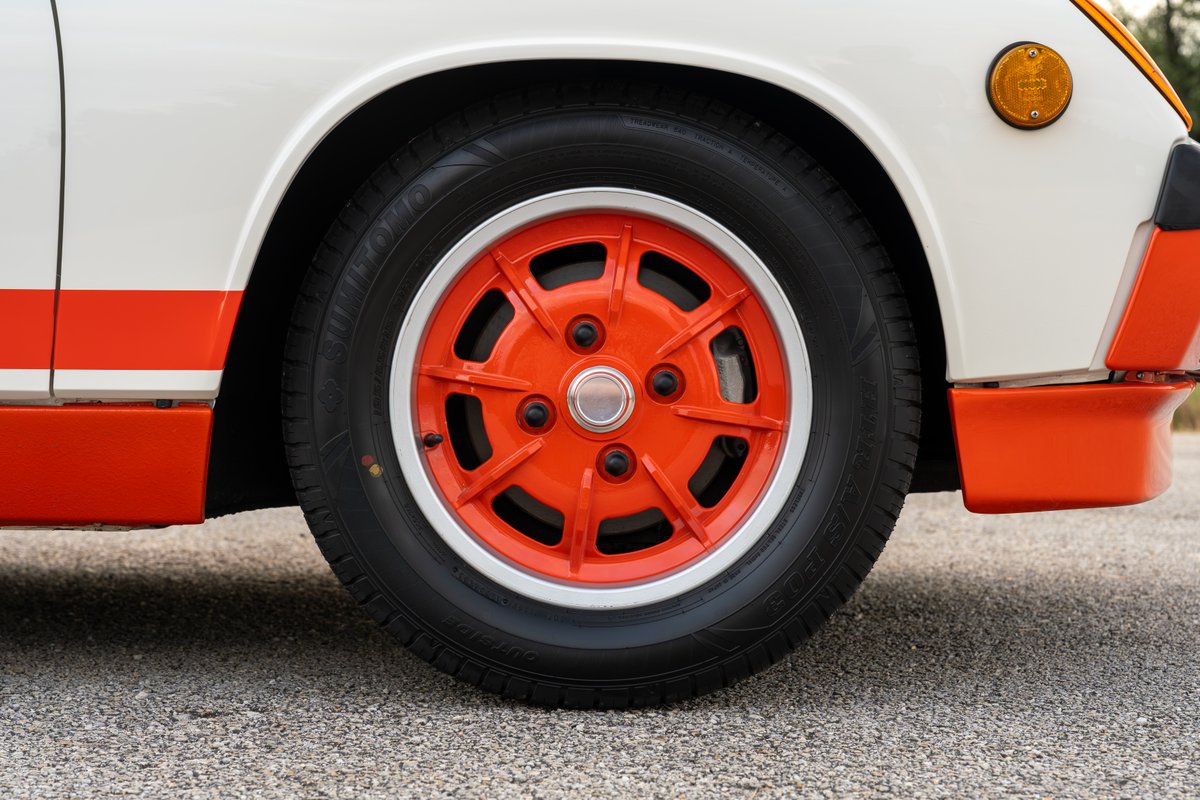 Close-up of a white 1974 Porsche 914 Can-Am with orange trim and a bright orange "creamsicle" rim.