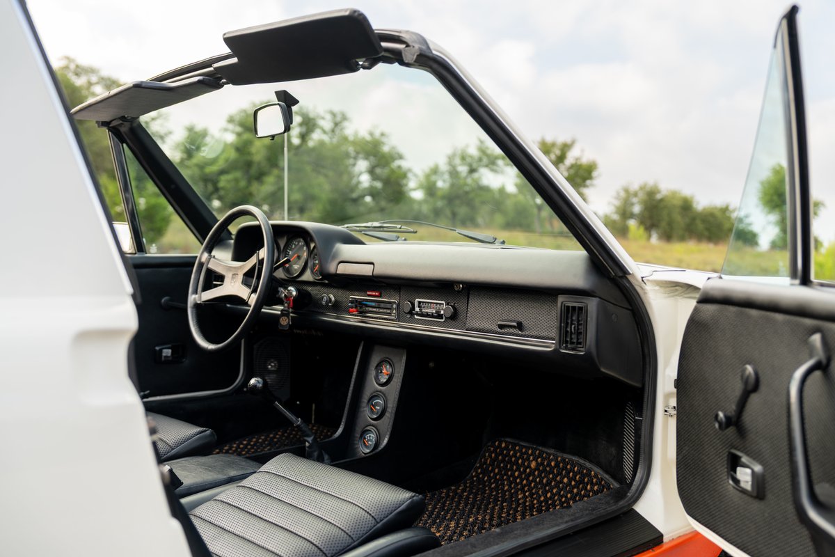 Interior view of a white 1974 Porsche 914 Can-Am LE with black leather seats.