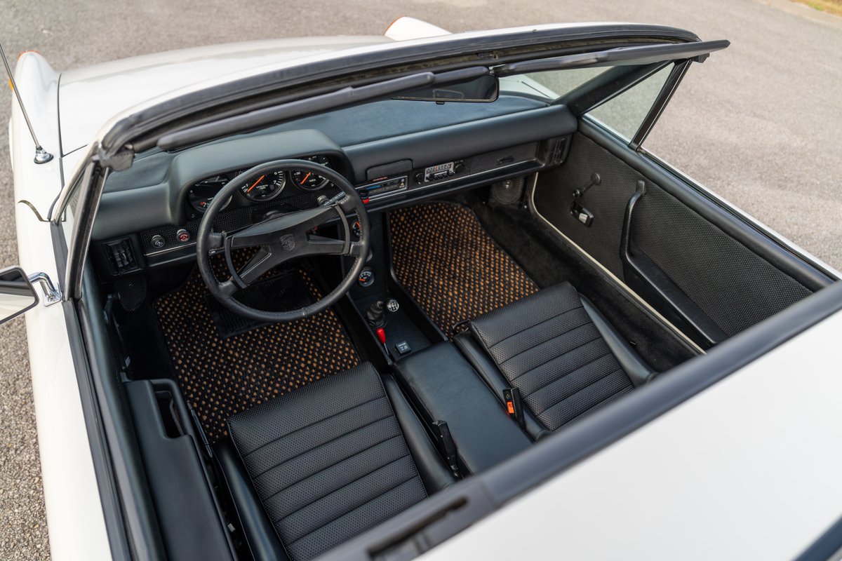 Interior of a white 1974 Porsche 914 Can-Am with black seats and tan floor mats.
