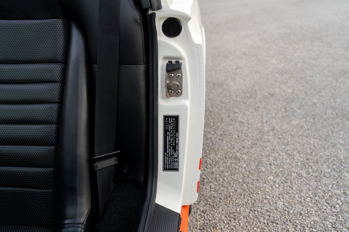 Detail of black perforated leather seat and white door trim with VIN plate on a 1974 Porsche 914 Can-Am LE.