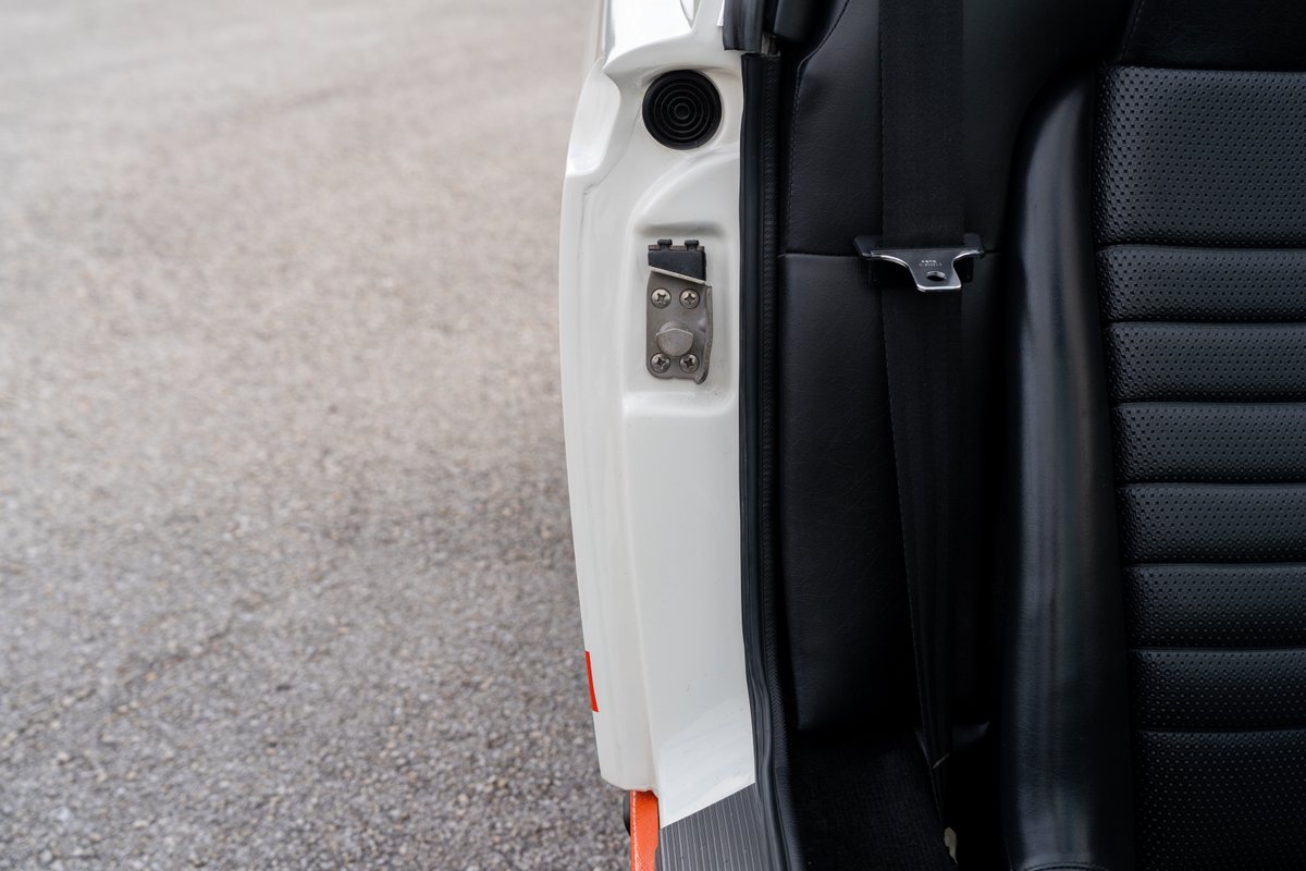 Close up of the door latch and black perforated seat in a white 1974 Porsche 914.