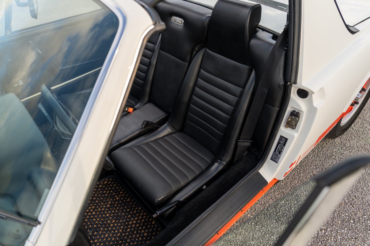 White 1974 Porsche 914 Can-Am LE interior. Black bucket seats, orange trim, and stripe livery.