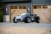 2000 Lotus 340R in grey with silver rims and a roll bar, parked in front of a garage.