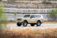 1975 International Harvester Scout II in tan with a white roof, lifted suspension, and chrome rims.