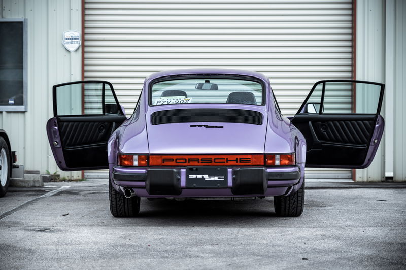 Vibrant purple Porsche 911SC (G-series) rear, doors open, showing black pleated interior and iconic PORSCHE reflector.