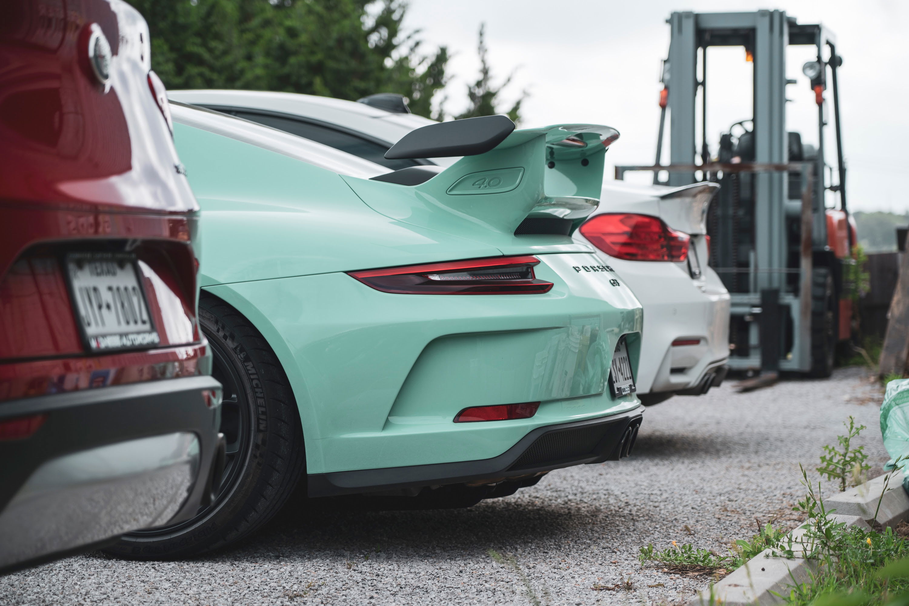 Mint Green Porsche 911 GT3 4.0 rear with swan-neck wing, black rims, and aggressive diffuser at a Coffee & Cars event.