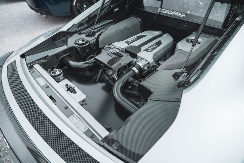 Overhead view of a white Audi R8 V8 FSI mid-engine, featuring carbon fiber trim panels & exposed engine bay components.