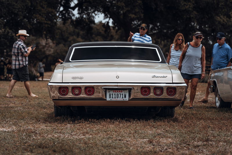 Rear view: champagne metallic 1968 Chevrolet Impala coupe. Triple round taillights, chrome bumper & trim, dark vinyl roof.