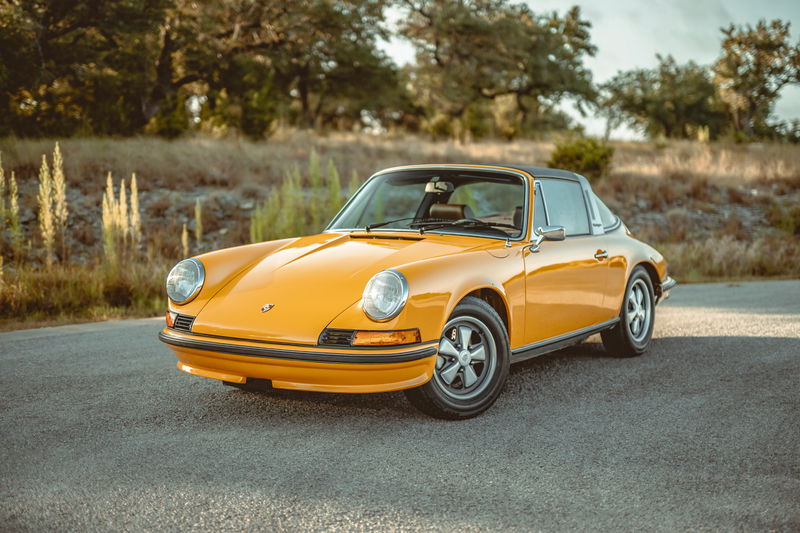 Front 3/4 view of a vibrant Signal Yellow 1973 Porsche 911S Targa, featuring iconic Fuchs alloy wheels and gleaming chrome trim.