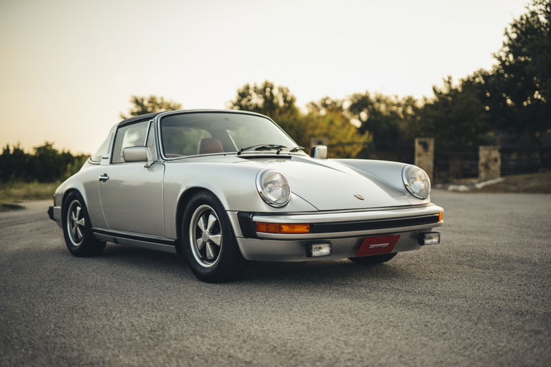 Silver Metallic 1977 Porsche 911S G-series Targa, featuring iconic Fuchs wheels, chrome trim, and a red interior.